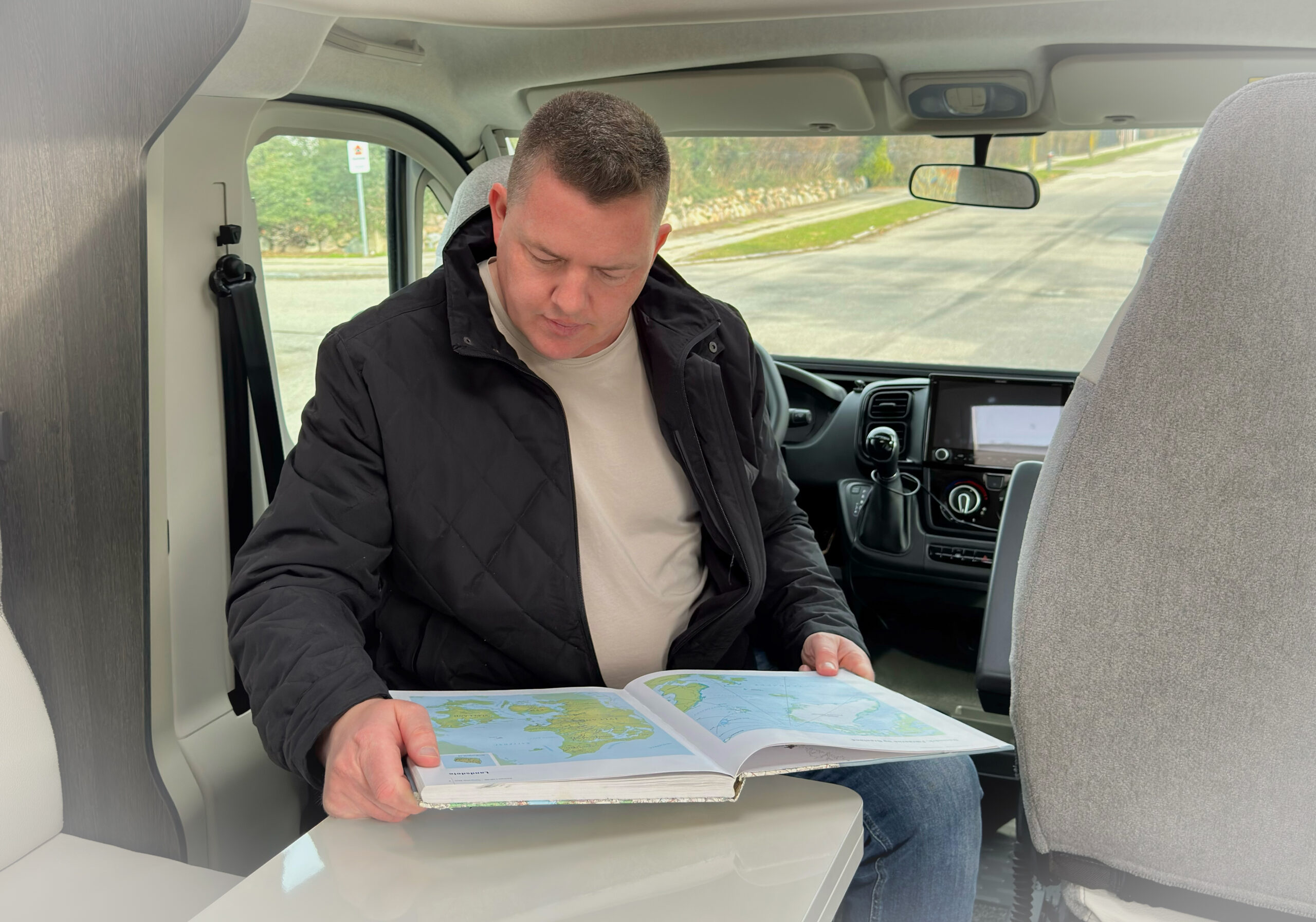 Rasmus Neslein reading a map inside a campervan while exploring Denmark